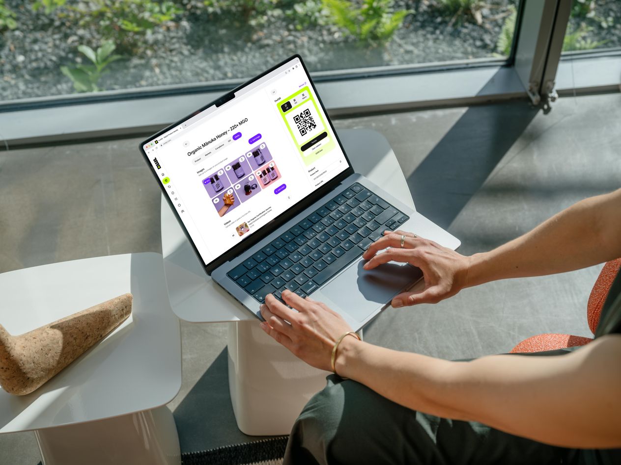 A laptop on a café table showing an OwlQR product page with its QR code.