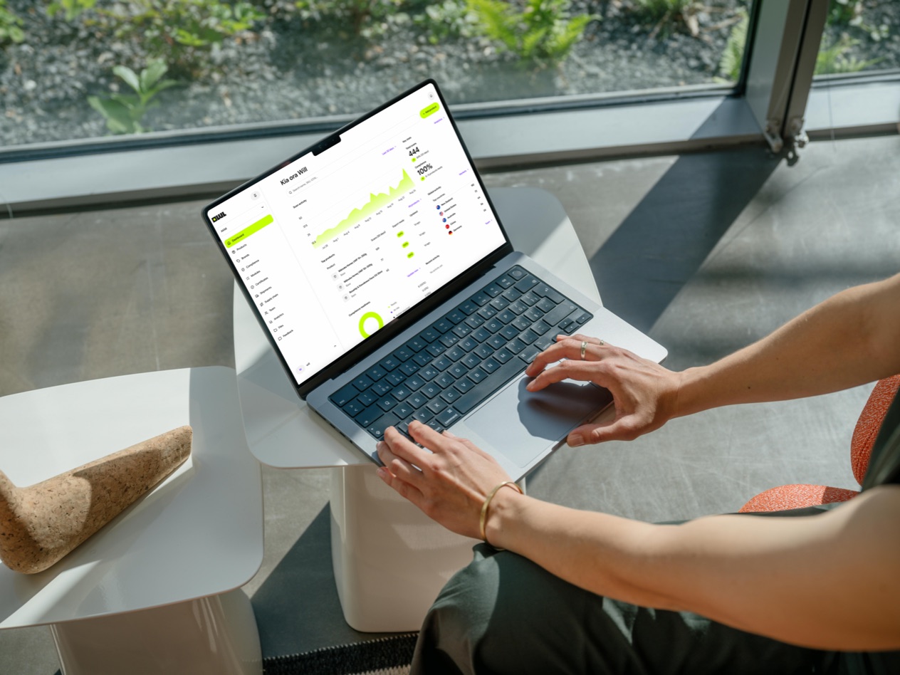 A laptop on a low table shows the OwlQR dashboard and its scan activity.
