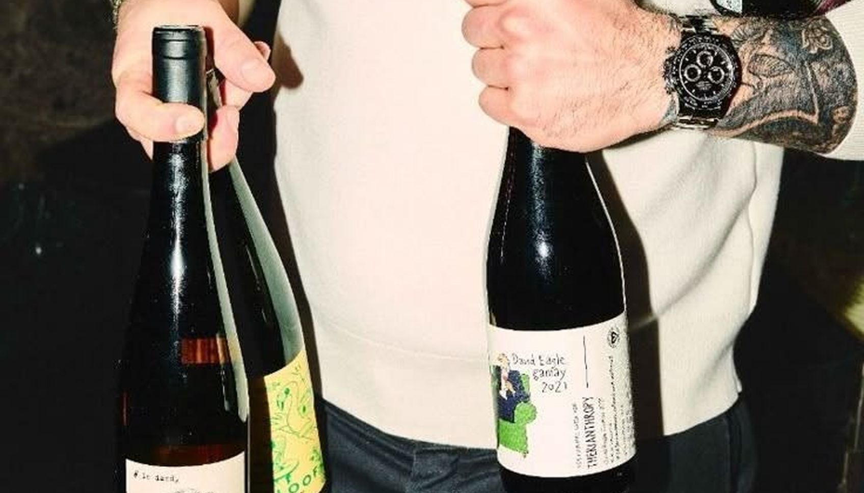A person carrying two unlabelled bottles of wine.