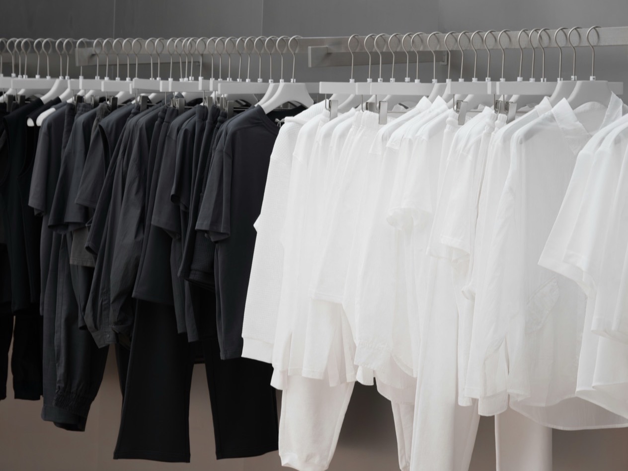 Dark and white garments on hangers along a shop rail.